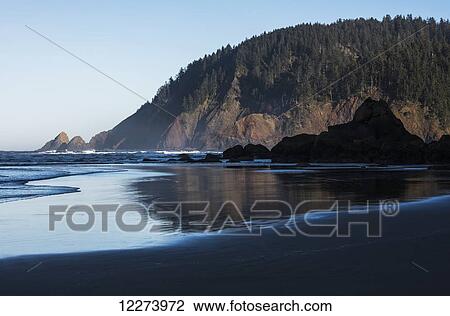 Stock Image - Morning sunlight warms Tillamook Head; Cannon Beach, Oregon, United States of America. Fotosearch