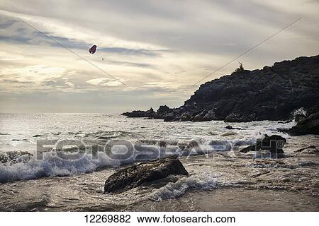 Stock Image - Paragliding over a rugged coastline on the Mexican Riviera; Ixtapa-Zihuatanejo, Guerrero, Mexico. Fotosearch
