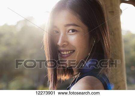 Stock Image - Portrait of a Chinese girl listening to music; Xiamen, Fujian province, China. Fotosearch
