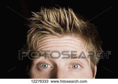 Stock Image - Portrait of a man with blue eyes and spiky hair on a black background; Edmonton, Alberta, Canada. Fotosearch