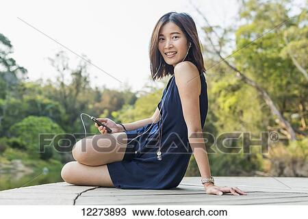 Portrait of a young chinese woman listening to music; Xiamen, Fujian province, China View Large Photo Image Stock Image - Portrait of a young chinese woman listening to music; Xiamen, Fujian province, China. Fotosearch