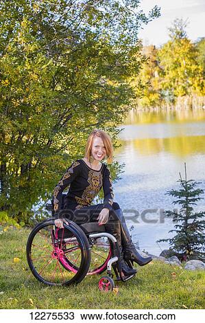 Stock Image - Portrait of a young disabled woman in a wheelchair in a city park in autumn; Edmonton, Alberta, Canada. Fotosearch