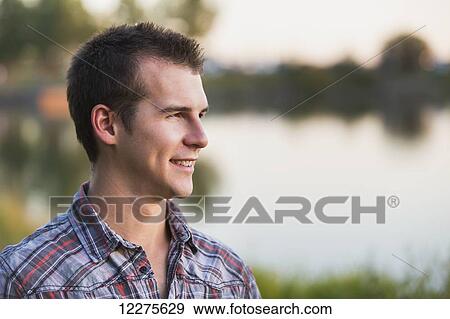Portrait of a young man beside a lake in autumn; St. Albert, Alberta, Canada View Large Photo Image Stock Photo - Portrait of a young man beside a lake in autumn; St. Albert, Alberta, Canada. Fotosearch