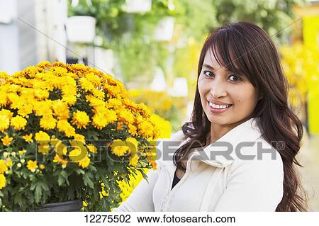 Portrait of a young woman looking at flowers in a greenhouse; St. Albert, Alberta, Canada View Large Photo Image Stock Image - Portrait of a young woman looking at flowers in a greenhouse; St. Albert, Alberta, Canada. Fotosearch