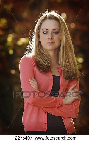 Stock Photo - Portrait of a young woman with arms crossed, looking confident; United States of America. Fotosearch