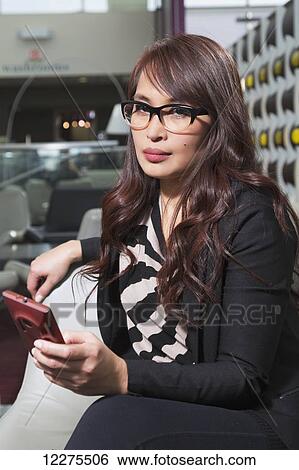Stock Photograph - Professional businesswoman checking her smart phone in a lounge area; St. Albert, Alberta, Canada. Fotosearch