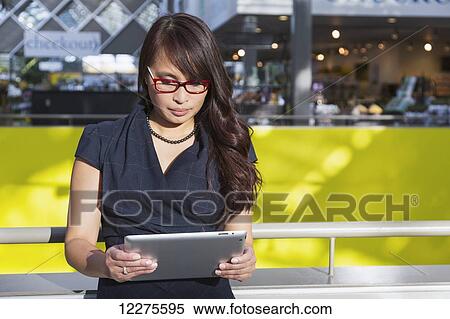Professional businesswoman using her tablet to conduct business in a shopping centre; St. Albert, Alberta, Canada View Large Photo Image Stock Photography - Professional businesswoman using her tablet to conduct business in a shopping centre; St. Albert, Alberta, Canada. Fotosearch