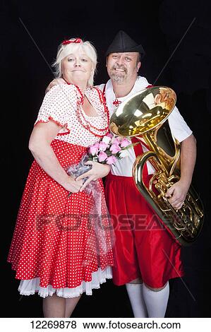 Proud, loving Austrian couple at talent show in traditional Bavarian dress holding flowers and tuba; Alberta, Canada View Large Photo Image Stock Photo - Proud, loving Austrian couple at talent show in traditional Bavarian dress holding flowers and tuba; Alberta, Canada. Fotosearch