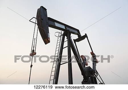 Stock Photo - Pumpjack at work on oilfield lease in a canola field in rural Alberta; St. Albert, Alberta, Canada. Fotosearch