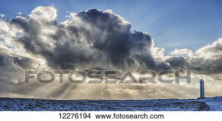 Rays of light shine out from behind the clouds in the skies above a lightnouse along the southern shore of Iceland; Iceland View Large Photo Image Picture - Rays of light shine out from behind the clouds in the skies above a lightnouse along the southern shore of Iceland; Iceland. Fotosearch