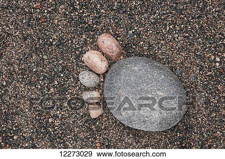 Stock Photo - Rocks placed in the shape of a footprint on a pebble beach; Thunder Bay, Ontario, Canada . Fotosearch