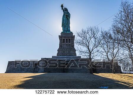 Sun setting behind the Statue of Liberty, Liberty Island; New York City, New York, United States of America View Large Photo Image Stock Image - Sun setting behind the Statue of Liberty, Liberty Island; New York City, New York, United States of America. Fotosearch