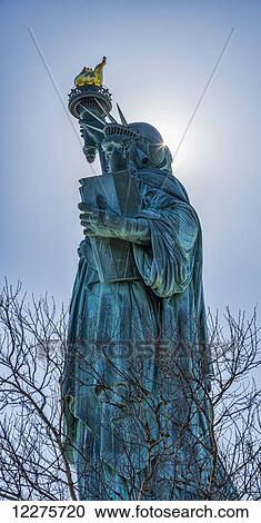Stock Image - Sun shining behind Statue of Liberty torch, Liberty Island; New York City, New York, United States of America. Fotosearch