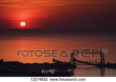 Sunrise over Lake Superior and the aerial lift bridge in Canal Park as seen from Enger Park; Duluth, Minnesota, United States of America View Large Photo Image Stock Image - Sunrise over Lake Superior and the aerial lift bridge in Canal Park as seen from Enger Park; Duluth, Minnesota, United States of America. Fotosearch