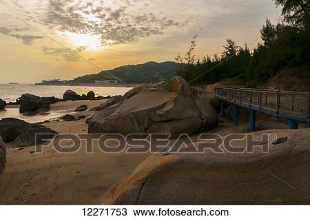 Stock Image - Sunset over Xiamen seaside; Xiamen, Fujian, China. Fotosearch