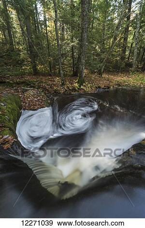 Stock Photo - The bottom of Little High Falls swirls around in this long exposure during autumn, near Bracebridge; Ontario, Canada. Fotosearch