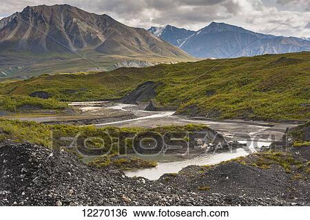 Thorofare River flowing next to the stone and vegatation covered Moldrow Glacier in Denali National Park and Preserve, Mount Eielson and the Alaska Range in the background; Alaska, United States of America View Large Photo Image Stock Photograph - Thorofare River flowing next to the stone and vegatation covered Moldrow Glacier in Denali National Park and Preserve, Mount Eielson and the Alaska Range in the background; Alaska, United States of America. Fotosearch