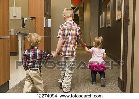 Three young children holding hands and walking down hallway in family dental clinic; Edmonton, Alberta, Canada View Large Photo Image Picture - Three young children holding hands and walking down hallway in family dental clinic; Edmonton, Alberta, Canada. Fotosearch