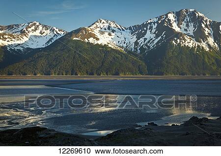 Stock Image - Tidal bore across Turnagain Arm of Cook Inlet, Chugach Mountains in the background; Alaska, United States of America. Fotosearch