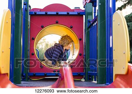 Stock Image - Toddler boy playing at a city playground at sunset; St. Albert, Alberta, Canada. Fotosearch