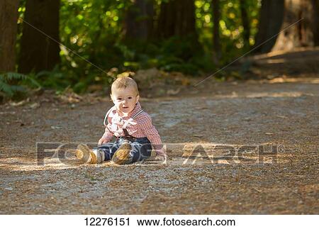 Stock Image - Toddler boy sitting on a path in a park; Langley, British Columbia, Canada. Fotosearch