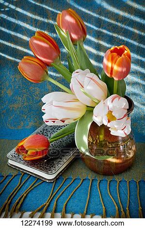 Tulips in a vase with a notebook on a tablecloth with tassels; Chilliwack, British Columbia, Canada View Large Photo Image Stock Photo - Tulips in a vase with a notebook on a tablecloth with tassels; Chilliwack, British Columbia, Canada. Fotosearch