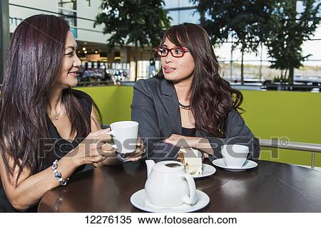 Stock Photography - Two businesswomen talking in a coffee shop in a shopping complex; St. Albert, Alberta, Canada. Fotosearch