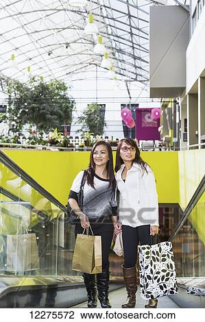 Two girlfriends out shopping together in a shopping mall; St. Albert, Alberta, Canada View Large Photo Image Stock Image - Two girlfriends out shopping together in a shopping mall; St. Albert, Alberta, Canada. Fotosearch