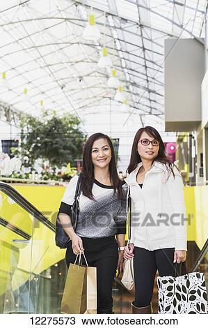 Stock Image - Two girlfriends out shopping together in a shopping mall; St. Albert, Alberta, Canada. Fotosearch
