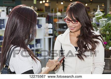 Stock Photo - Two girlfriends out shopping together in a shopping mall; St. Albert, Alberta, Canada. Fotosearch