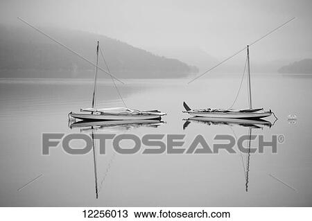 Two sailboats reflected in a calm, misty lake; Ontario, Canada View Large Photo Image Stock Image - Two sailboats reflected in a calm, misty lake; Ontario, Canada. Fotosearch