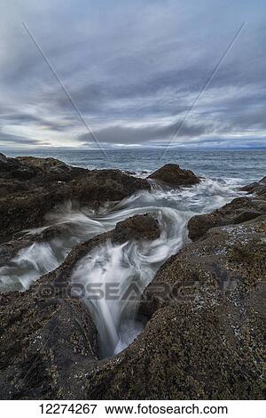 Stock Photo - Water rushes over the volcanic bedrock near Tow Hill, Haida Gwaii at sunrise, Naikoon Provincial Park; Masset, British Columbia, Canada. Fotosearch