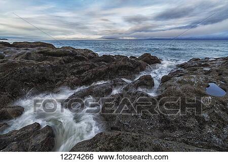 Stock Photograph - Water rushes over the volcanic bedrock near Tow Hill, Haida Gwaii at sunrise, Naikoon Provincial Park; Masset, British Columbia, Canada. Fotosearch