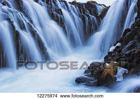 Waterfalls flowing over rugged rock cliffs; Bruarfoss, Iceland View Large Photo Image Picture - Waterfalls flowing over rugged rock cliffs; Bruarfoss, Iceland. Fotosearch