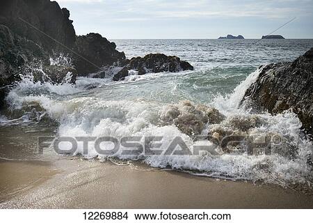 Waves crashing on the shore and rock formations in the ocean in the distance; Ixtapa-Zihuatanejo, Guerrero, Mexico View Large Photo Image Picture - Waves crashing on the shore and rock formations in the ocean in the distance; Ixtapa-Zihuatanejo, Guerrero, Mexico. Fotosearch
