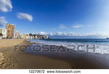 Stock Image - Waves rolling into the sand along the coastline; Benidorm, Spain. Fotosearch