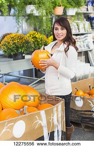 Woman looking at pumpkins in a greenhouse; St. Albert, Alberta, Canada View Large Photo Image Stock Photograph - Woman looking at pumpkins in a greenhouse; St. Albert, Alberta, Canada. Fotosearch