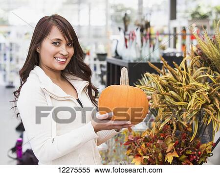 Stock Photography - Woman looking at pumpkins in a greenhouse; St. Albert, Alberta, Canada. Fotosearch