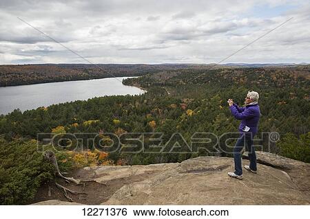 Woman takes pictures of Rock Lake from atop Booth's Rock, Algonquin Park; Ontario, Canada View Large Photo Image Stock Photograph - Woman takes pictures of Rock Lake from atop Booth's Rock, Algonquin Park; Ontario, Canada. Fotosearch