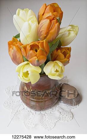 Stock Photo - Yellow and orange tulips in a ceramic vase; British Columbia, Canada. Fotosearch