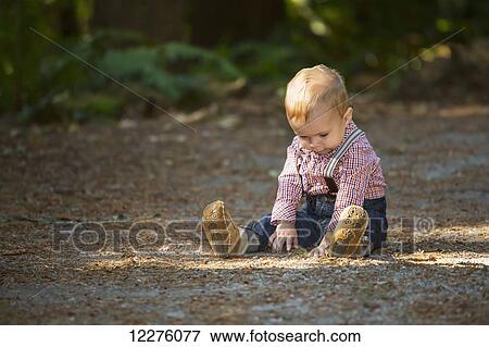 Stock Photo - Young boy sitting on a path in a park; Langley, British Columbia, Canada. Fotosearch