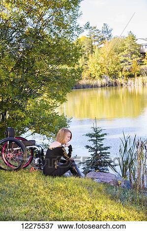 Young disabled woman sitting beside her wheelchair in a city park in autumn; Edmonton, Alberta, Canada View Large Photo Image Stock Photo - Young disabled woman sitting beside her wheelchair in a city park in autumn; Edmonton, Alberta, Canada. Fotosearch