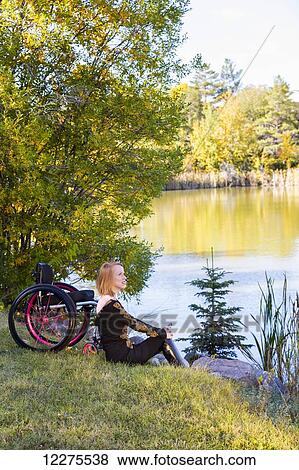 Young disabled woman sitting beside her wheelchair in a city park in autumn; Edmonton, Alberta, Canada View Large Photo Image Stock Photo - Young disabled woman sitting beside her wheelchair in a city park in autumn; Edmonton, Alberta, Canada. Fotosearch