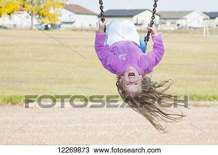 Young girl on swing in a playground in residential community on a cool, windy fall day; Three Hills, Alberta, Canada View Large Photo Image Stock Image - Young girl on swing in a playground in residential community on a cool, windy fall day; Three Hills, Alberta, Canada. Fotosearch