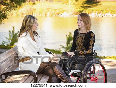 Young paraplegic woman and her friend spending quality time together in a city park in autumn; Edmonton, Alberta, Canada View Large Photo Image Stock Image - Young paraplegic woman and her friend spending quality time together in a city park in autumn; Edmonton, Alberta, Canada. Fotosearch
