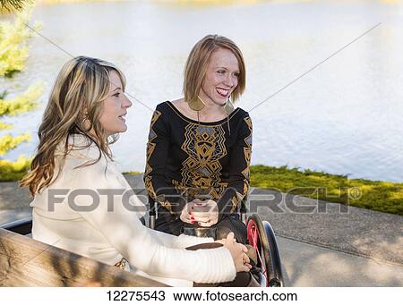 Young paraplegic woman and her friend spending quality time together in a city park in autumn; Edmonton, Alberta, Canada View Large Photo Image Stock Image - Young paraplegic woman and her friend spending quality time together in a city park in autumn; Edmonton, Alberta, Canada. Fotosearch