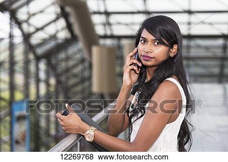 Young professional businesswoman talking on her smart phone in office building; Edmonton, Alberta, Canada View Large Photo Image Stock Photo - Young professional businesswoman talking on her smart phone in office building; Edmonton, Alberta, Canada. Fotosearch