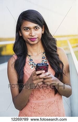 Stock Photo - Young professional businesswoman texting on her smart phone; Edmonton, Alberta, Canada. Fotosearch