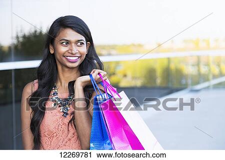 Stock Image - Young professional businesswoman with shopping bags in downtown setting; Edmonton, Alberta, Canada. Fotosearch
