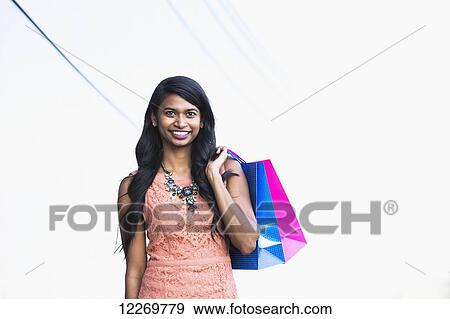 Stock Photo - Young professional businesswoman with shopping bags in downtown setting; Edmonton, Alberta, Canada. Fotosearch